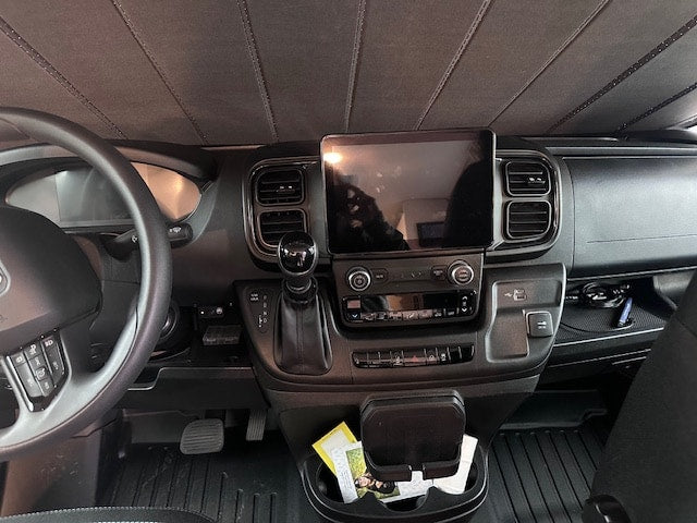  overlooking a serene lake and dense pine forest.|Driver's view of an RV rental interior: large tablet display