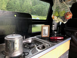 Cozy RV rental kitchenette with "Tacos" sign, fresh fruit, and rainy forest views. Perfect for camping.