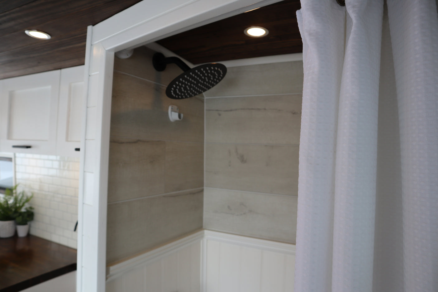 Modern RV rental: See its stylish interior with a tiled shower and an adjacent compact kitchen. Ready for adventures!