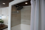 Modern RV rental: See its stylish interior with a tiled shower and an adjacent compact kitchen. Ready for adventures!