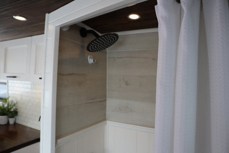 Modern RV rental: See its stylish interior with a tiled shower and an adjacent compact kitchen. Ready for adventures!