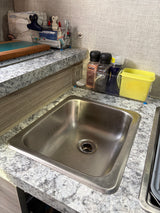Functional RV rental kitchen area featuring a stainless steel sink, countertop organizers, spices, and cleaning supplies.