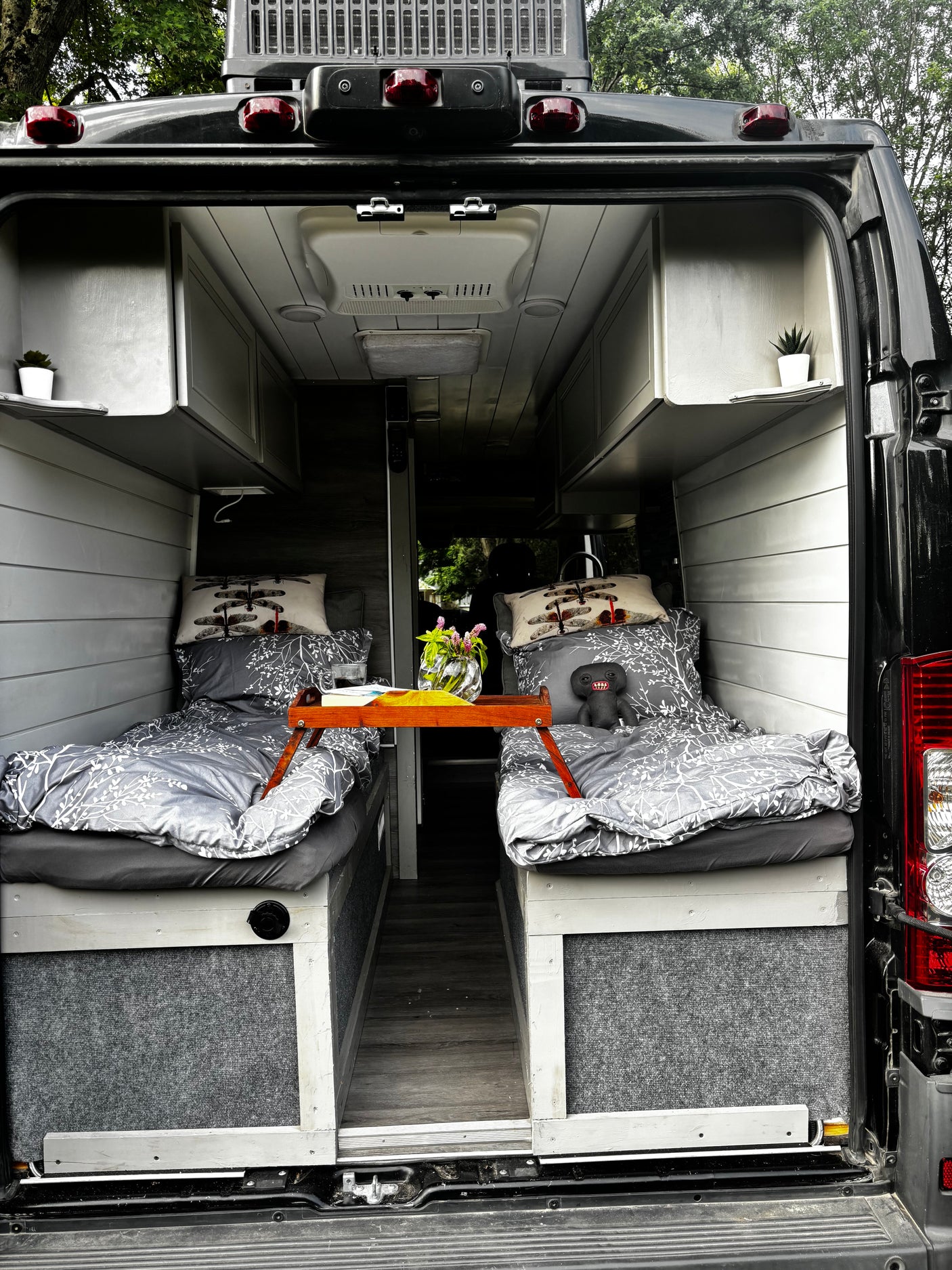 Cozy RV rental interior: twin beds, overhead storage & a charming setup for travel in this customized camper van.