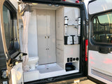 Inside an RV rental: compact bathroom with toilet/shower, built-in storage, and Thule ladder.