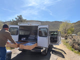 Man using custom pull-out drawers from his utility truck camper. A unique RV rental for rugged outdoor adventures.