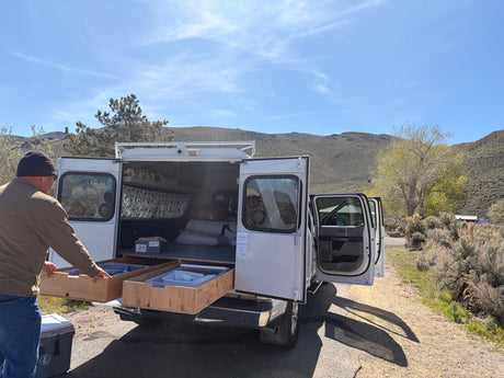 Man using custom pull-out drawers from his utility truck camper. A unique RV rental for rugged outdoor adventures.