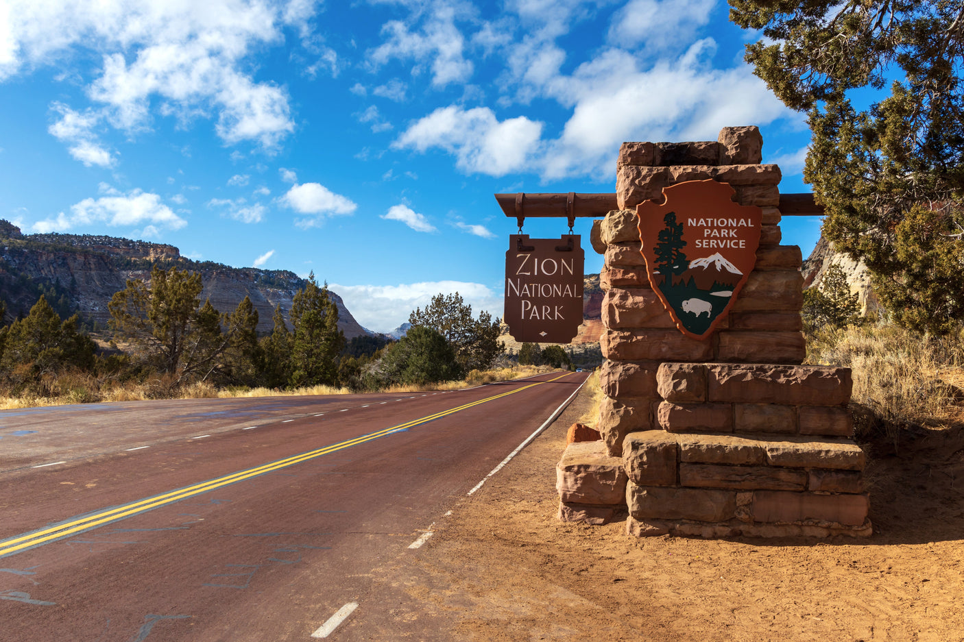 Zion National Park entrance sign & red road. Start your RV rental journey to explore stunning landscapes.