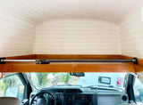 RV rental interior: White paneled cab-over bunk/storage above the Ford dashboard, with a securing bar.