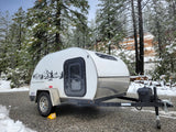 Winter wonderland rv rental: A cozy teardrop camper parked in a snowy forest.