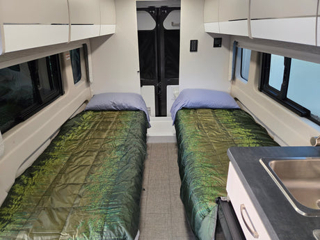 This rv rental offers a cozy interior with twin beds, a compact kitchen sink, and overhead storage, ideal for road trips.