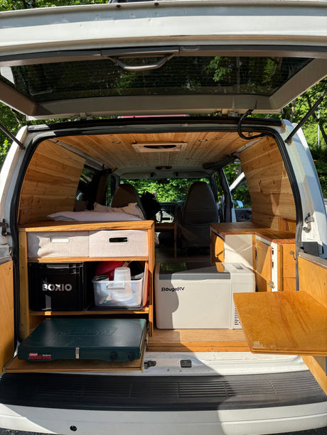 Explore this custom wood-paneled camper van interior, perfect for an RV rental adventure with built-in bed & kitchen.