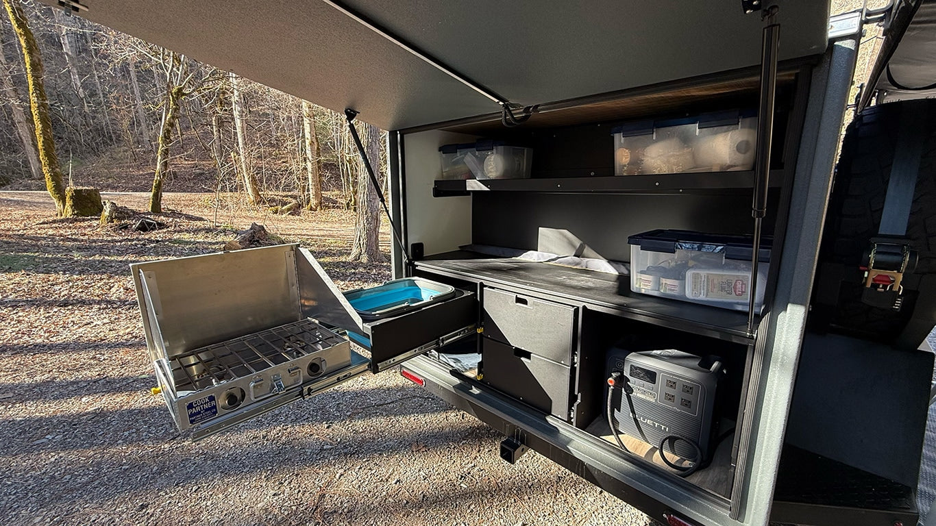 RV rental camp kitchen: pull-out stove, sink, organized storage, and BLUETTI power station for outdoor cooking & adventure.