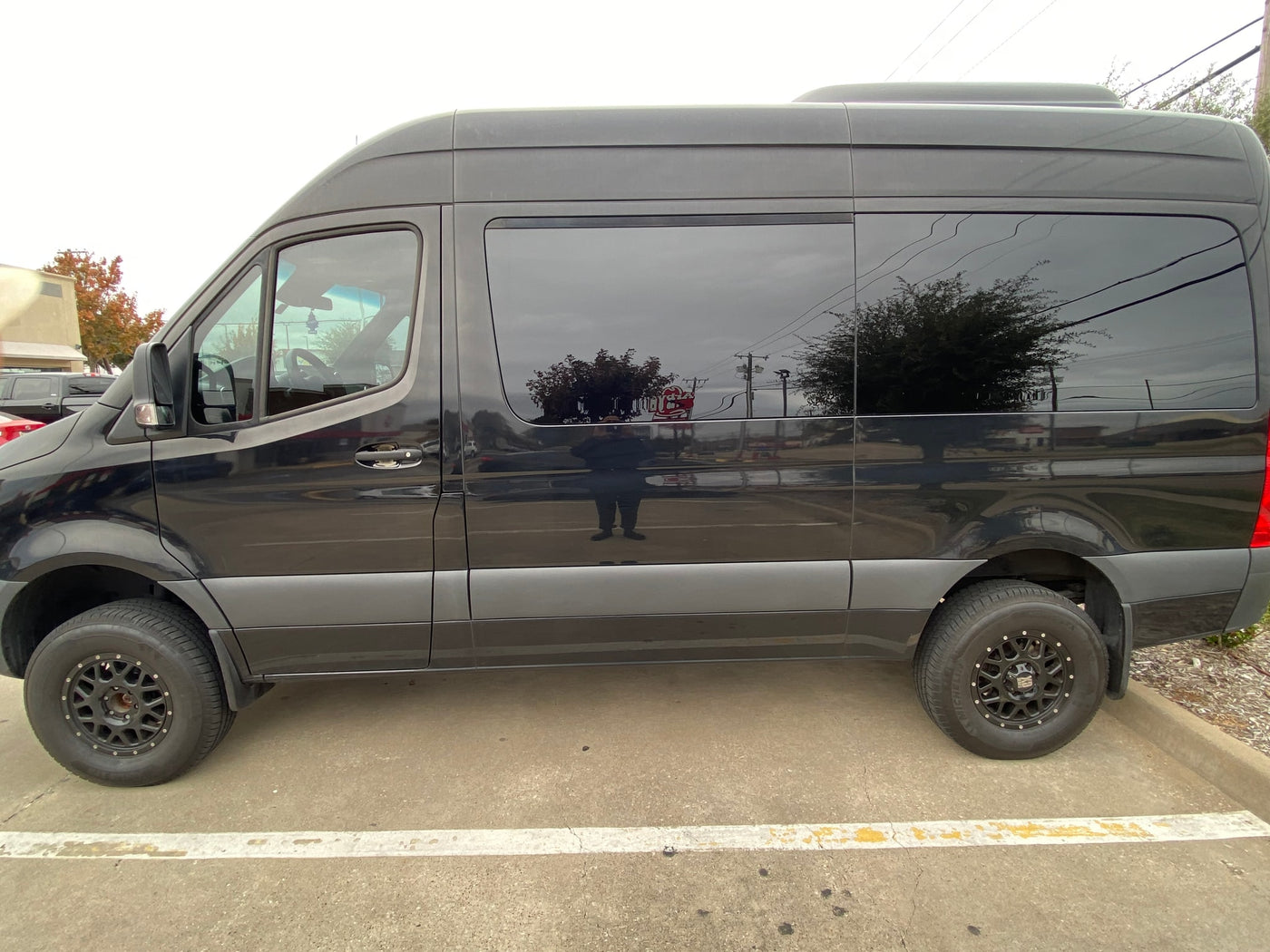  custom wheels & step. Great rv rental parked near Arby's.|Side view of a sleek black van — photo 2