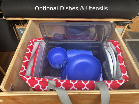RV rental: Optional dishes & utensils, neatly organized in a wooden compartment with a clear bin & red storage bag.