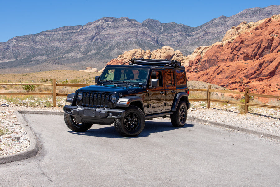 Black Jeep Wrangler in Red Rock Canyon, NV, amidst mountains and vibrant red rocks. Ideal for exploration, enhancing your RV rental journey.