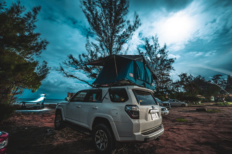 This white SUV with a deployed rooftop tent at a scenic ocean campsite, ready for an RV rental adventure. — photo 8