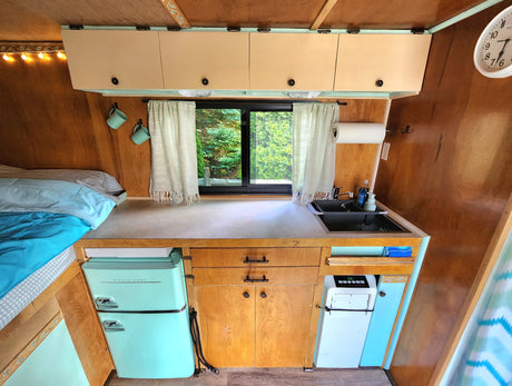 Step into this charming retro RV rental! Features a full kitchenette, a unique mint fridge, and a cozy bed area.