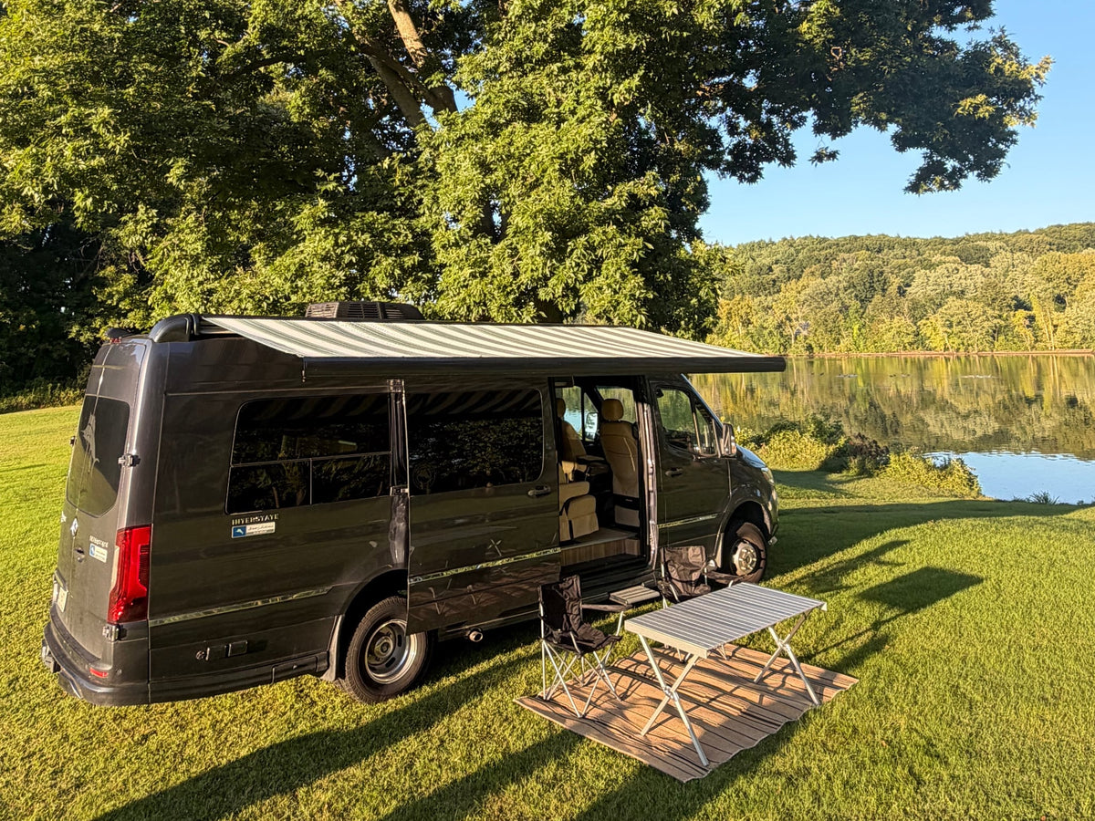  parked on lush grass.|An rv rental camper van with an awning extended — photo 16