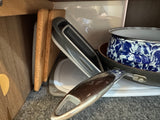 RV rental kitchen: stored pots, pan, cork boards, and a collapsible strainer. Compact & travel-ready.