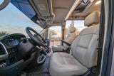 Interior of an RV rental cab. Driver's seat, steering wheel, and passenger seat overlook a scenic desert with cacti.