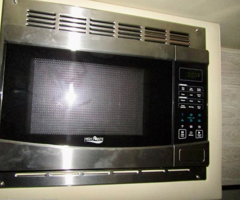 Shiny stainless steel microwave with a black door & digital clock (0:00), built into an RV rental kitchen cabinet. — photo 7