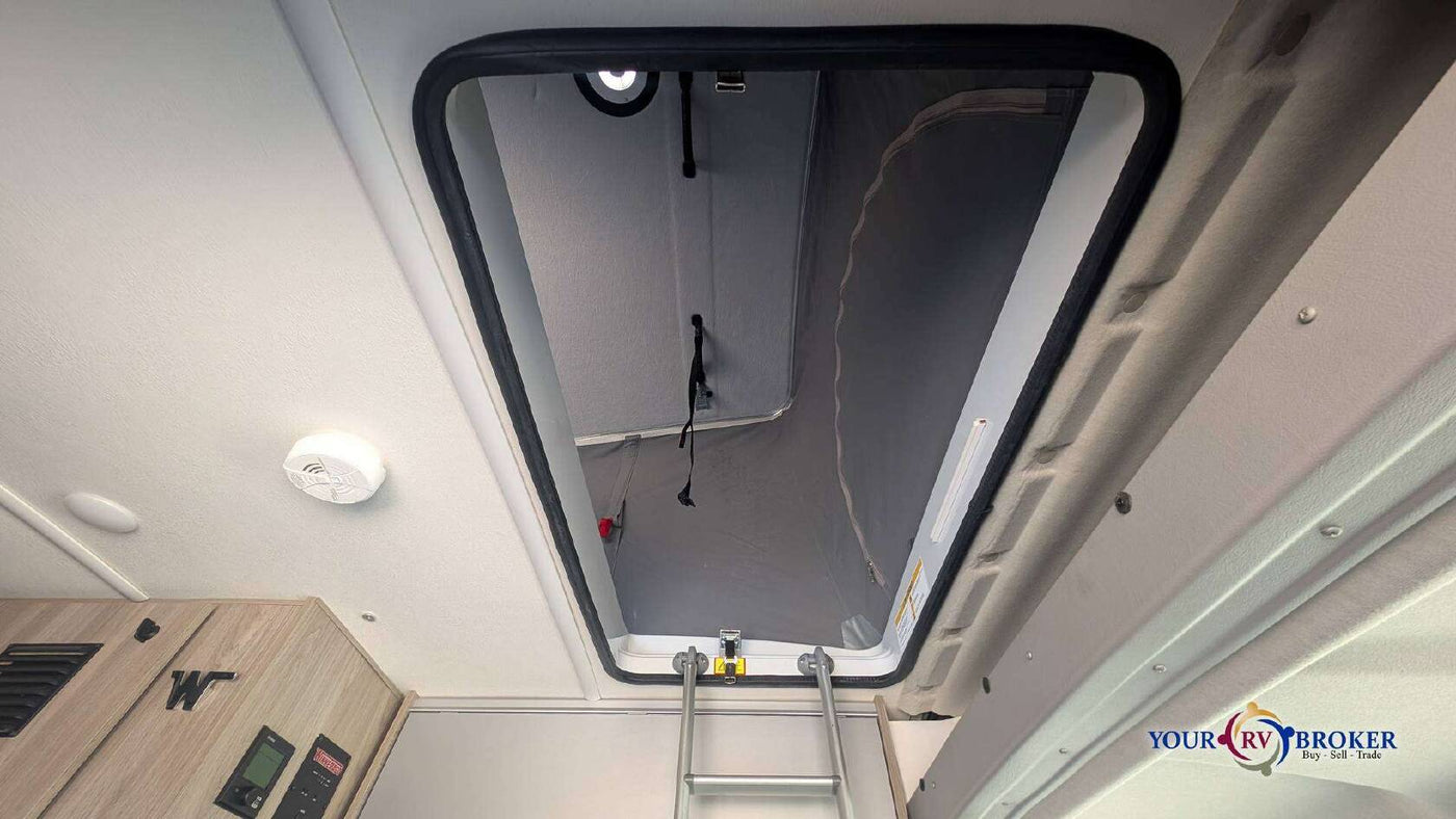  and light-colored counter space.|Inside an RV rental: a space-saving wet bath featuring a toilet and integrated shower for convenience.|Experience a compact RV rental interior with a kitchen sink — photo 13