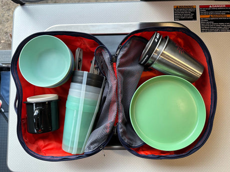 Portable kitchen gear with bowls, plates, and mugs, packed in a case, ready for an RV rental trip, beside safety warnings.