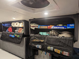 RV rental overhead storage organized with kitchen and bedding essentials, plus toilet paper, in a camper van.