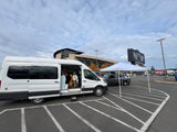 White RV rental camper van parked at a stadium, with people inside for a tailgate event. Ideal for game day experiences.