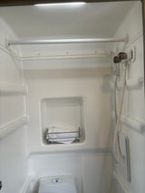 This RV rental bathroom features a compact shower, toilet, and mounted basket, designed for efficient travel comfort.