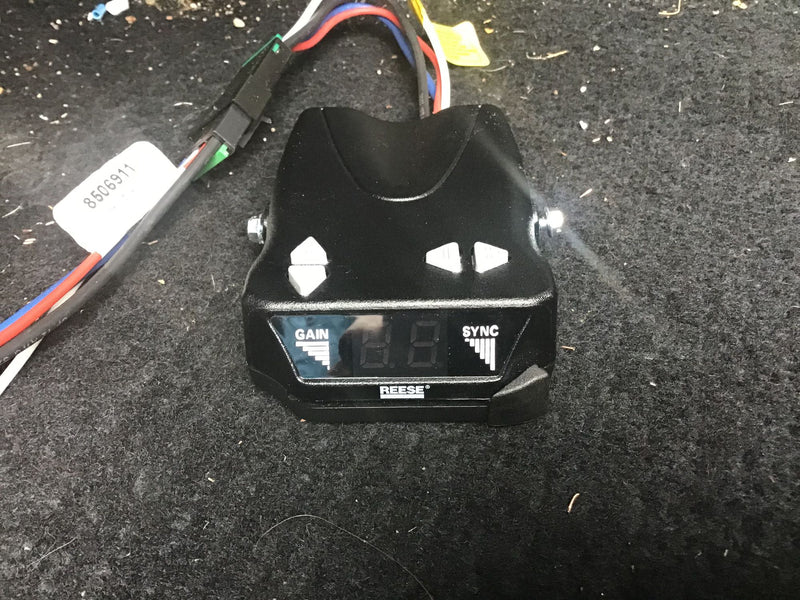 Black Reese trailer brake controller for RV rental, with 'GAIN' and 'SYNC' labels, on dark carpet. — photo 18