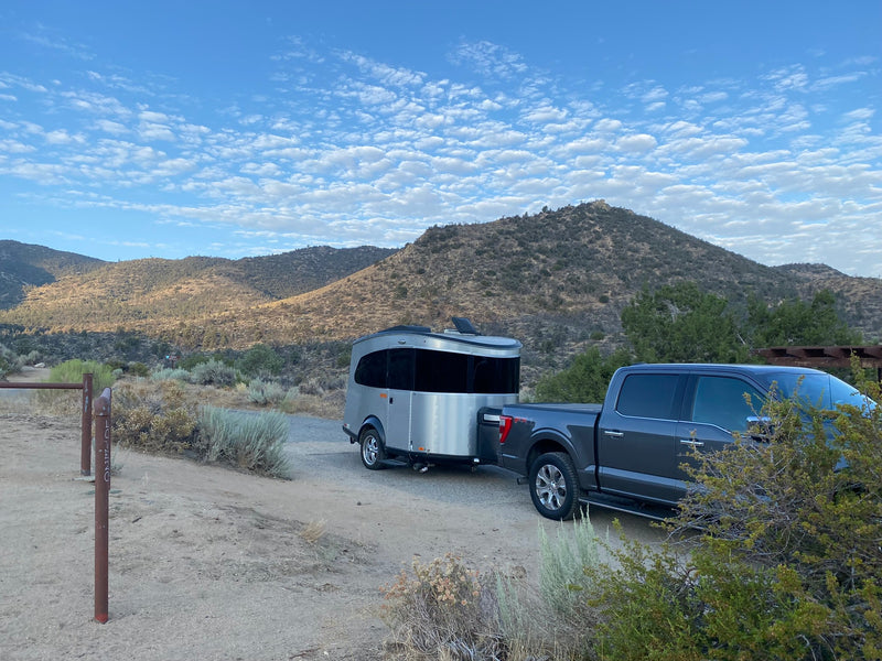 Scenic RV rental journey: A truck tows a sleek travel trailer in mountains under a beautiful sky. Perfect for outdoor adventures. — photo 12