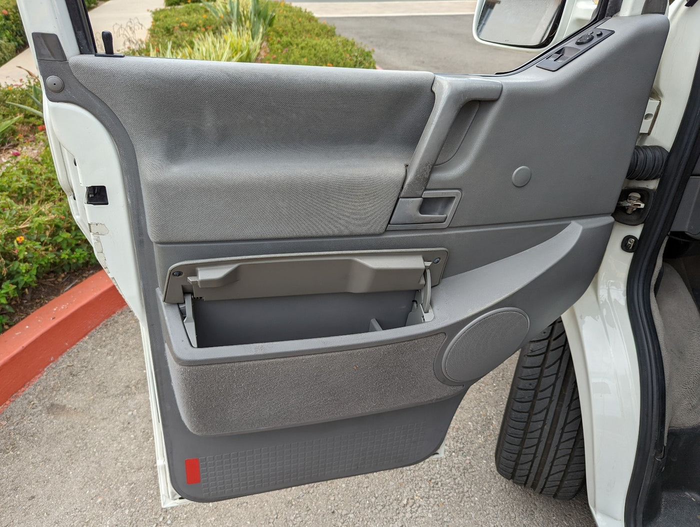 Interior view of a gray RV rental door panel, showcasing an open storage bin, door handle, and speaker. — photo 14
