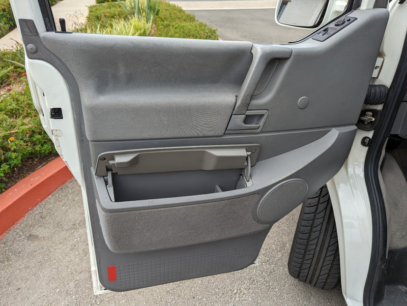 Interior view of a gray RV rental door panel, showcasing an open storage bin, door handle, and speaker. — photo 14