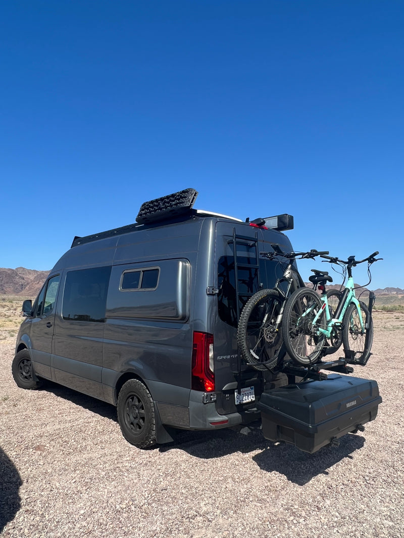 This dark grey RV rental camper van with e-bikes, roof rack, and cargo box is parked in a sunny desert landscape. — photo 5