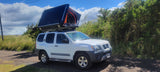 White Nissan Xterra SUV with a deployed rooftop tent, great for your RV rental adventures.