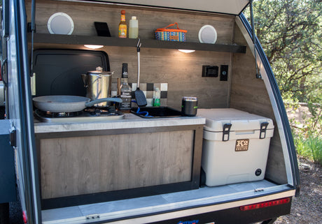 This RV rental's outdoor kitchen is ready for adventure! Features a stove, sink, and K2 cooler, perfect for camp meals.