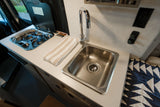 Inside this RV rental, find a compact kitchen with a stainless steel sink, chrome faucet, and gas stove.