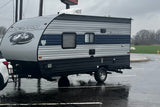 A sleek grey and blue Wolf Pup travel trailer, great rv rental for outdoor adventures, parked on a rainy day.
