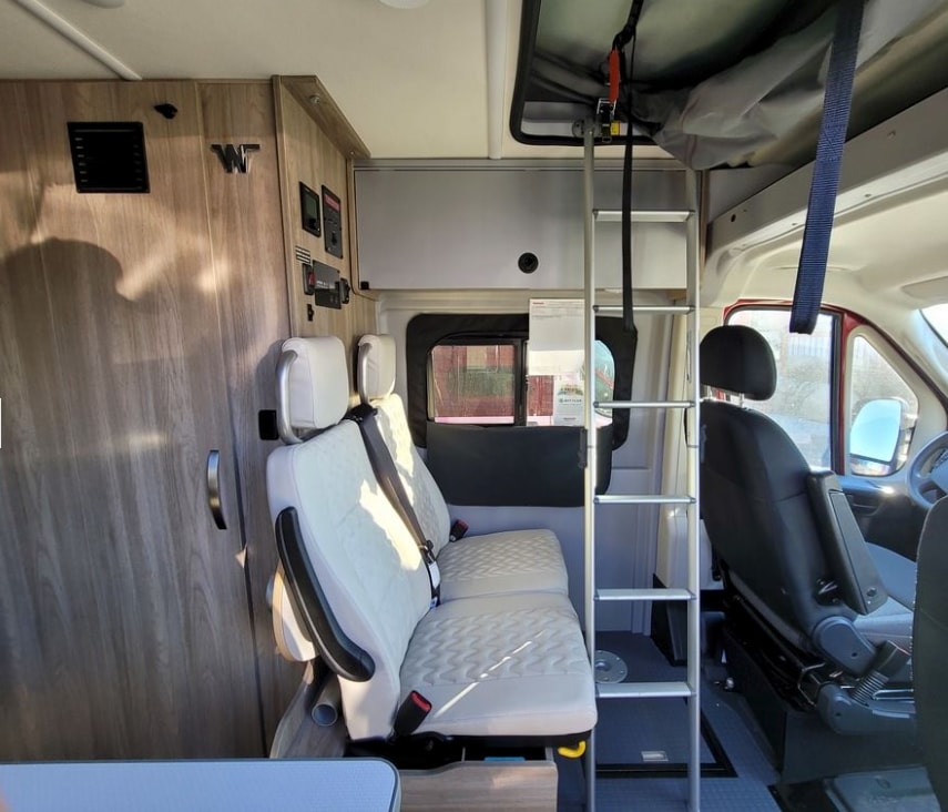  parked in a scenic forest with its pop-top extended.|Red Winnebago Solis camper van with pop-top raised