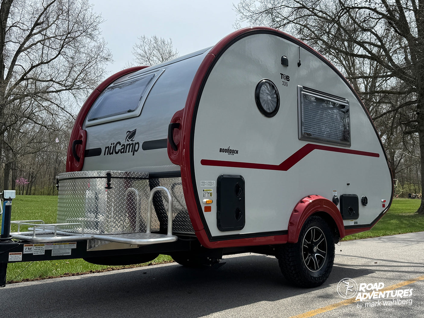 This nuCamp T@B 320 Boondock Edition teardrop camper, a perfect rv rental, is ready for adventure with its striking red and white design.