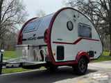 This nuCamp T@B 320 Boondock Edition teardrop camper, a perfect rv rental, is ready for adventure with its striking red and white design.
