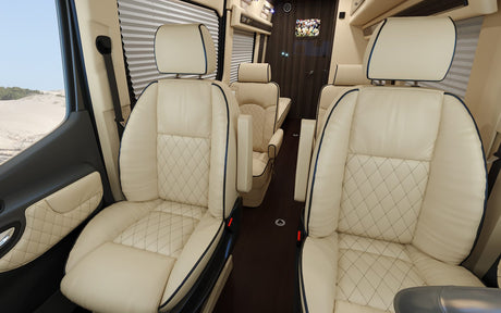 Elegant RV rental interior: cream leather seats with diamond stitching and dark piping offer luxurious comfort for travel.
