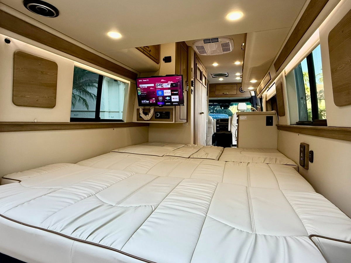 and colorful mugs secured in foam for your RV rental journey.|Well-equipped rv rental interior: compact kitchen with induction cooktop & flexible sleeping berths.|RV rental's comfortable interior features a flexible bed/lounge with soft white cushions — photo 13