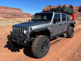 Rugged gray Jeep Gladiator, equipped for overlanding, parked in a red rock desert landscape. Consider this for an RV rental adventure.