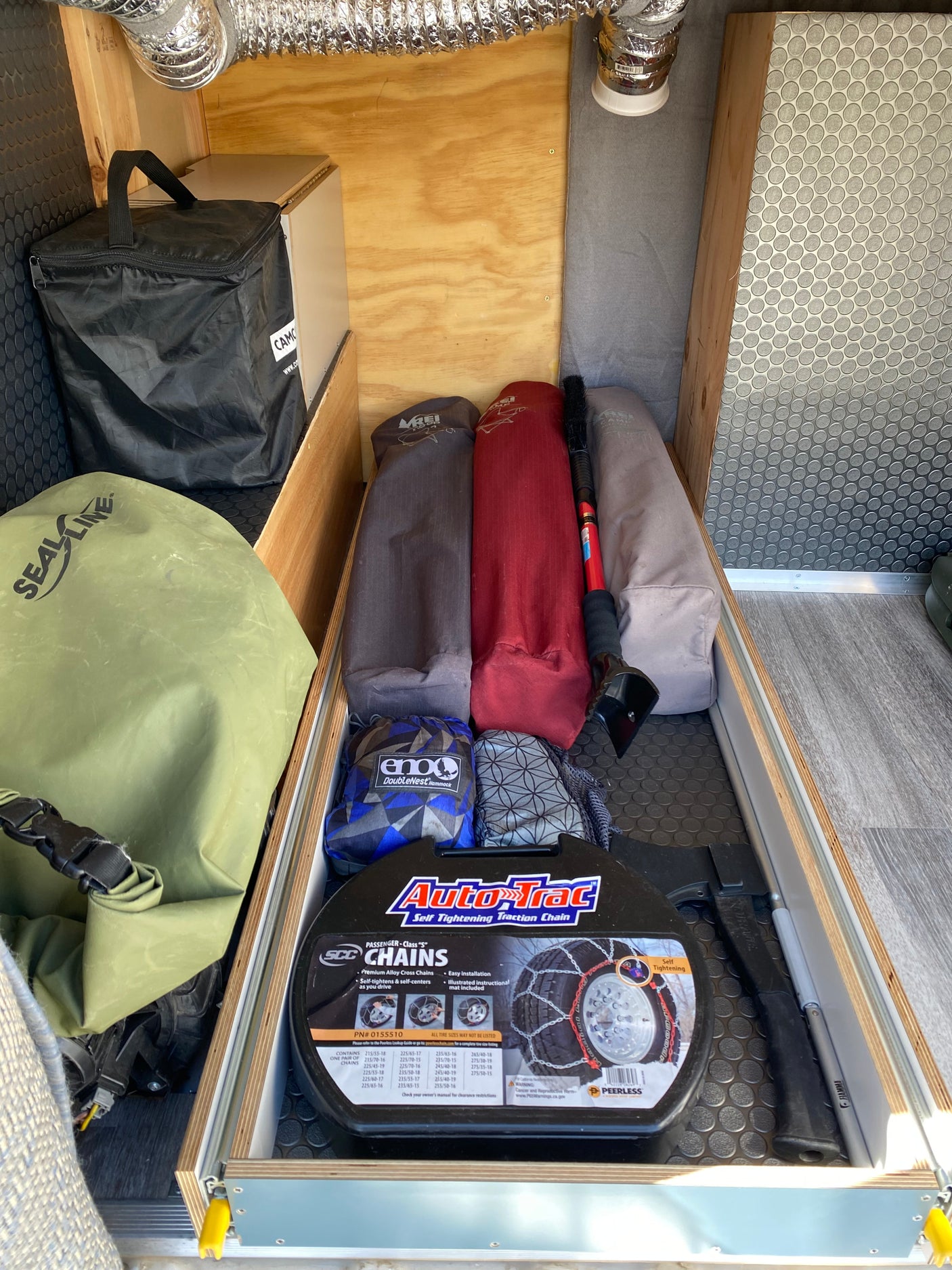 RV rental storage packed with camping gear (hammock, sleeping bags), ice scraper, and Auto-Trac snow chains for any adventure.
