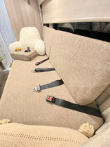 RV rental interior: Comfortable bench seat with multiple seatbelts, a cozy reading pillow, and drink caddy for travel.