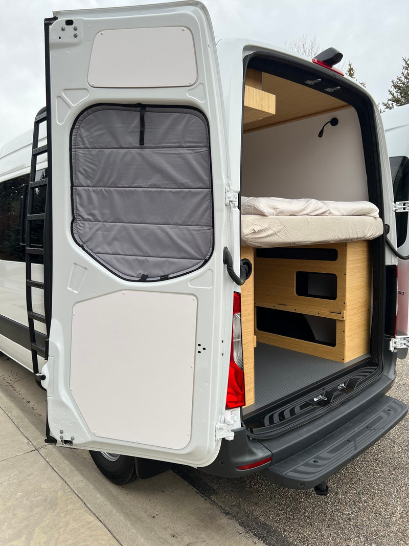 Rear view of an RV rental: white camper van with open doors, showcasing a cozy bed, modular storage, and exterior ladder. — photo 15