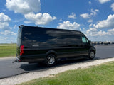 Luxury black Mercedes-Benz Sprinter van, ideal for RV rental, parked at an airfield on a bright, cloudy day.