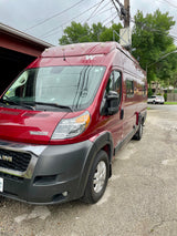 A vibrant red Winnebago camper van, possibly an RV rental, parked on a driveway.